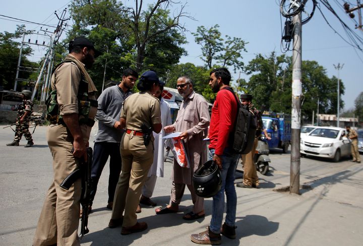 A police officer checks papers of people on a road during restrictions in Srinagar August 6, 2019.