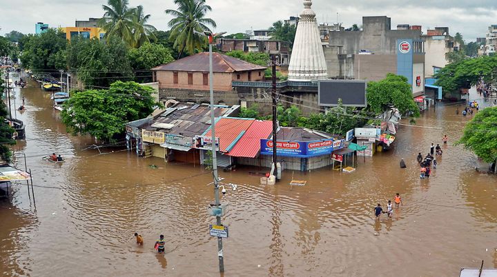 In this picture taken on August 6, 2019 people wade through a flooded street in Sangli. 