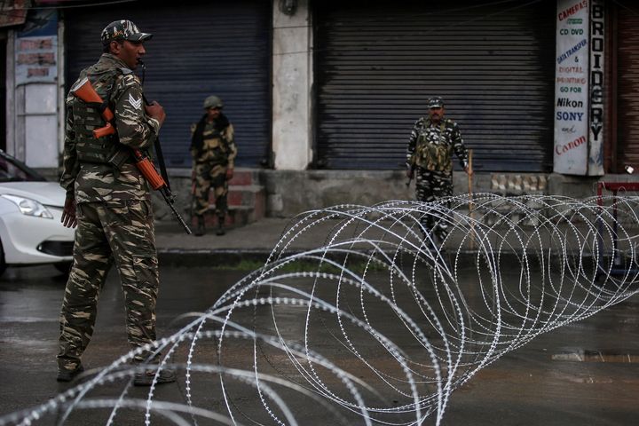 Security forces personnel stand guard next to concertina wire laid across a road during restrictions after the government scrapped special status for Kashmir, in Srinagar August 7, 2019.