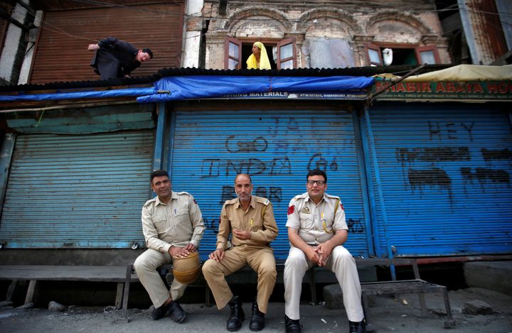 Policemen sit in front of closed shops during restrictions in Srinagar, August 6, 2019. 