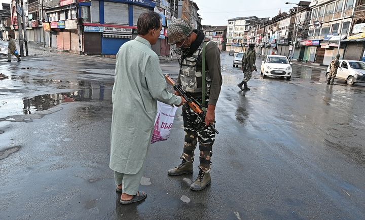 A security personnel checks the bag of a Kashmiri man during a curfew in Srinagar on August 8, 2019.