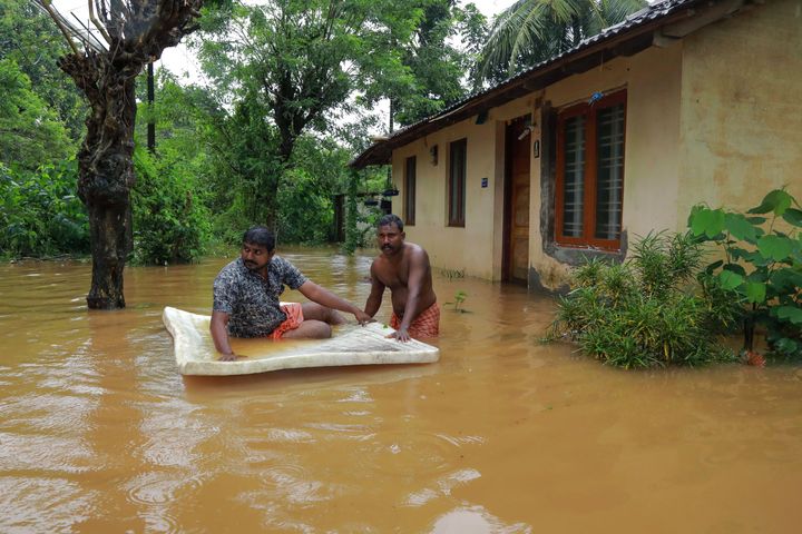 Men pass through flood waters at Eloor area in Ernakulam district,Kerala, on August 9, 2019. 