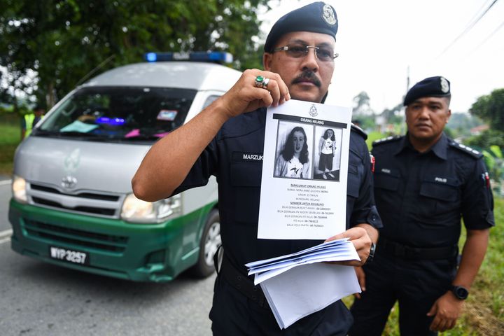 A police officer holding a leaflet bearing a portrait of the missing 15-year-old 