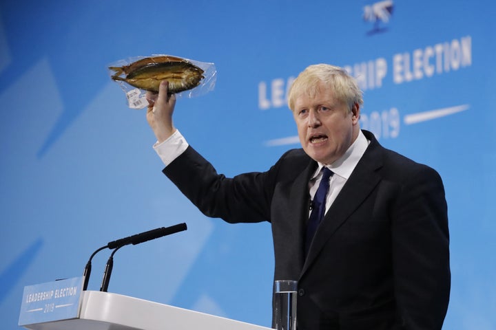 British Prime Minister Boris Johnson holds up a smoked kipper in plastic packaging. 