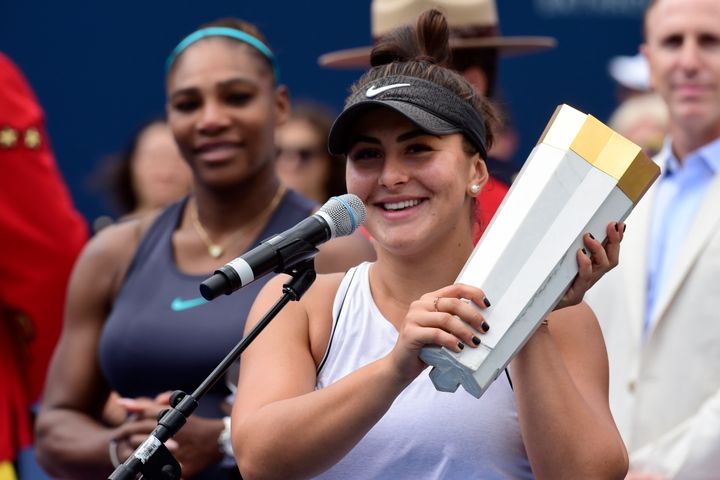 Bianca Andreescu holds the winner's trophy as Serena Williams looks on after Williams had to retire from the final of the Rogers Cup tennis tournament in Toronto on Aug. 11, 2019. 