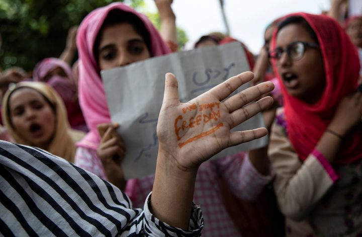 A Kashmiri woman shows her hand with a message as others shout slogans during a protest after the scrapping of the special constitutional status for Kashmir by the government, in Srinagar, August 11, 2019. 