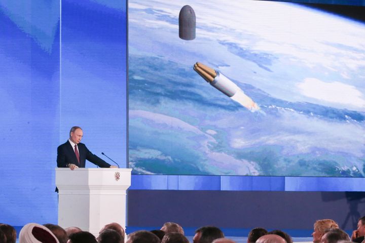 Russian President Vladimir Putin speaks in front of an animation of new nuclear missile technology in a 2018 address in Mosco