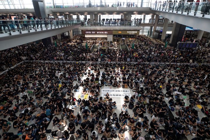 Protesters surround banners that read: "Those on the street today are all warriors!" center top, and "Release all the detainees!" during a sit-in rally at the arrival hall of the Hong Kong International airport on Aug. 12, 2019. 