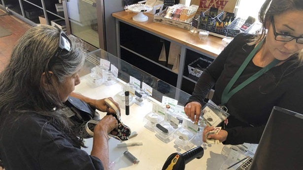 Tina Bernal, left, who uses cannabis to relieve chronic pain, buys a vial of marijuana at Minerva cannabis dispensary in New