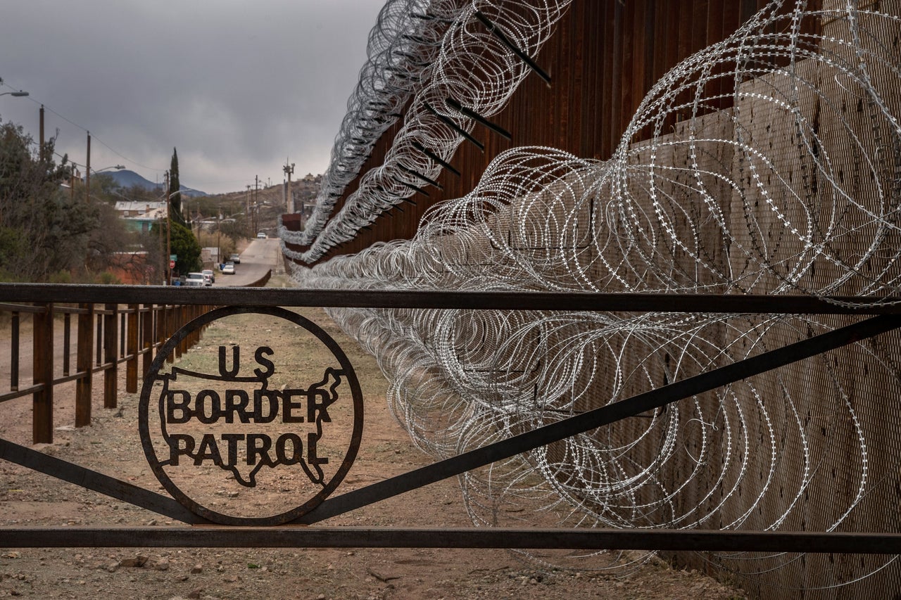 A metal fence marked with the U.S. Border Patrol insignia prevents people from getting close to the barbed/concertina wire covering the larger border fence in Nogales, Arizona, on Feb. 9, 2019.