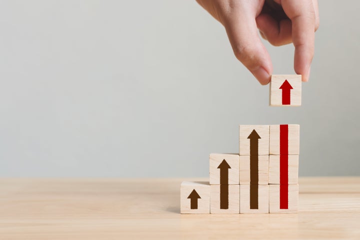 Hand arranging wood block stacking as step stair with arrow up. Ladder career path concept for business growth success process