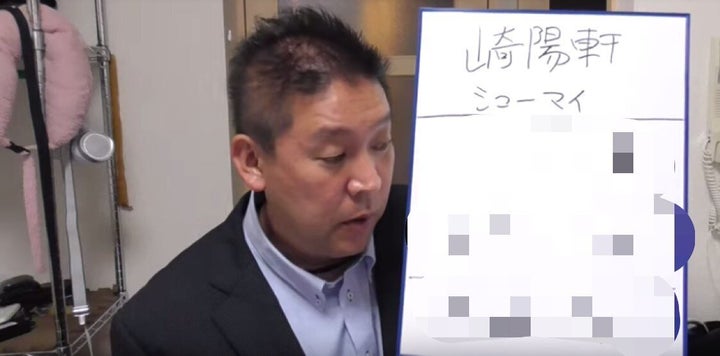 「崎陽軒以外に3社のスポンサー企業の社名が書かれたフリップを手に、不買運動を宣言した立花氏。（編集部注：画像を一部加工しています）