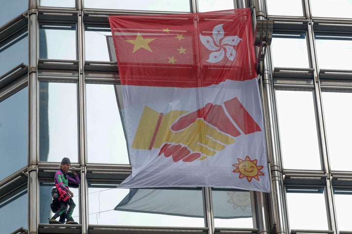 French “spiderman” climber Alain Robert hoisted the flag to encourage reconciliation between China and Hong Kong,