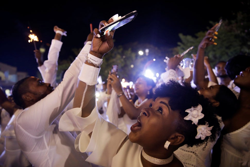 Παρευρισκόμενοι, στην εκδήλωση Haiti Diner en Blanc, στο Cap Haitien της Αϊτής, που πραγματοποιήθηκε στις 10 Αυγούστου, βγάζουν φωτογραφίες από τα βεγγαλικά στον ουρανό.