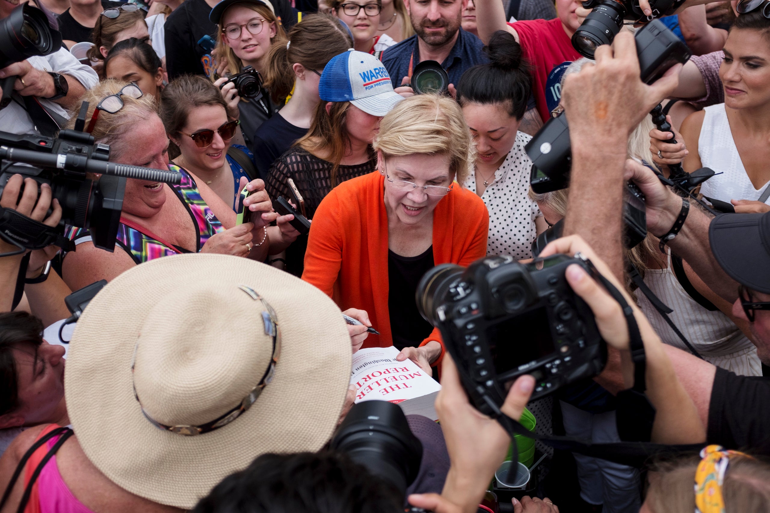 Sen. Elizabeth Warren (D-Mass.) signs a copy of the Mueller report for one of her supporters at the Iowa State Fair on Aug. 1