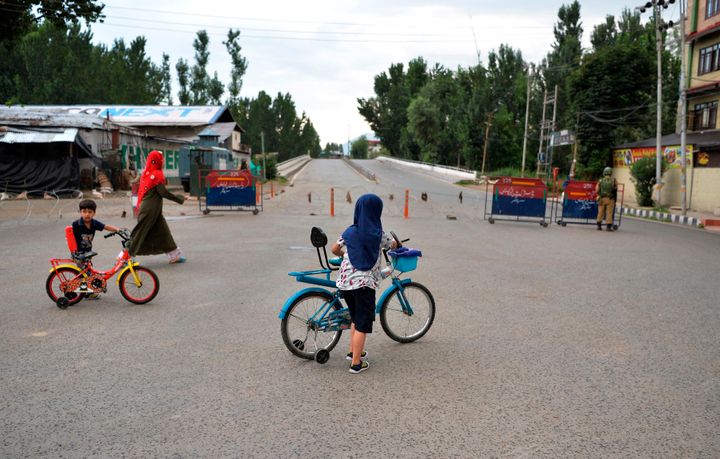 In this picture taken on August 9, 2019, a woman and children with their bikes cross a deserted street in Srinagar.
