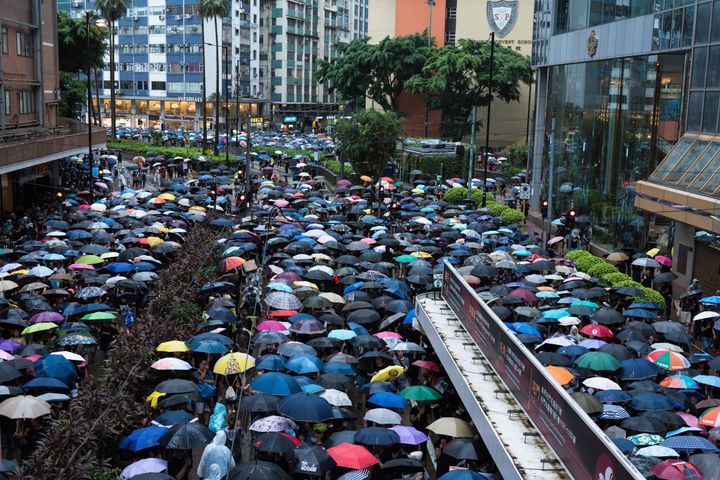 Protesters stand shoulder to shoulder while holding umbrellas during a peaceful demonstration. 