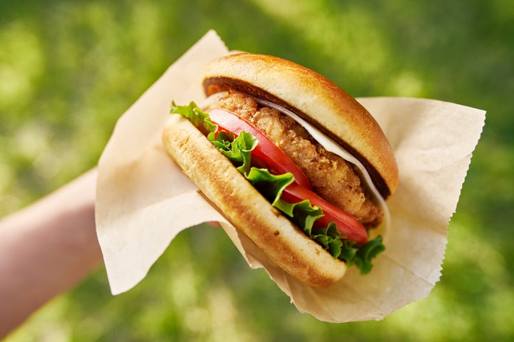 A woman holding a chicken sandwich.