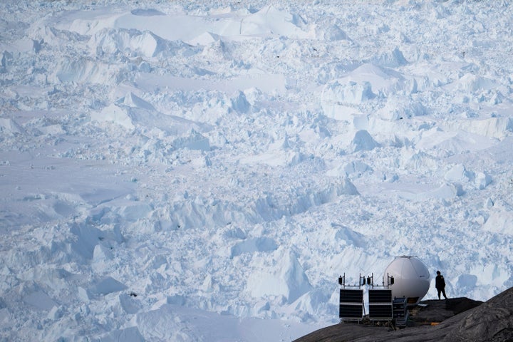 In this Aug. 16, 2019, photo, a woman stands next to an antenna at an NYU base camp at the Helheim glacier in Greenland. Summ