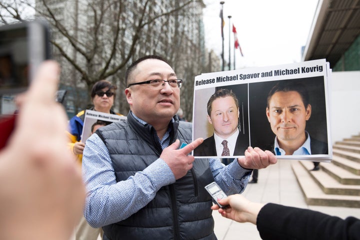 Louis Huang of Vancouver Freedom and Democracy for China holds photos of Michael Spavor and Michael Kovrig outside British Columbia Supreme Court, in on Mar. 6, 2019