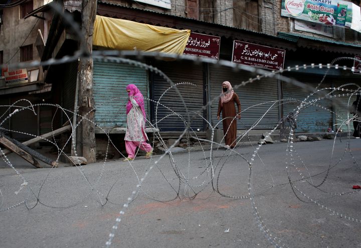 Kashmiri women walk past concertina wire laid across a road during restrictions after the scrapping of the special constitutional status for Kashmir by the Indian government, in Srinagar, August 20, 2019. REUTERS/Adnan Abidi