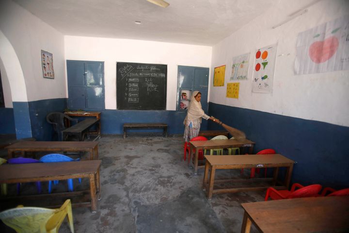 A Kashmiri school staff member cleans a deserted classroom in Srinagar on August 19.