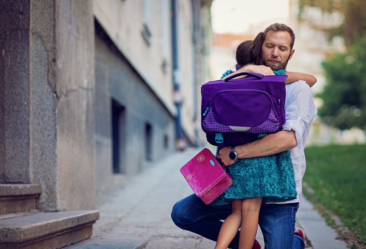 Father is sending his sad daughter to school for first time and trying to relax her