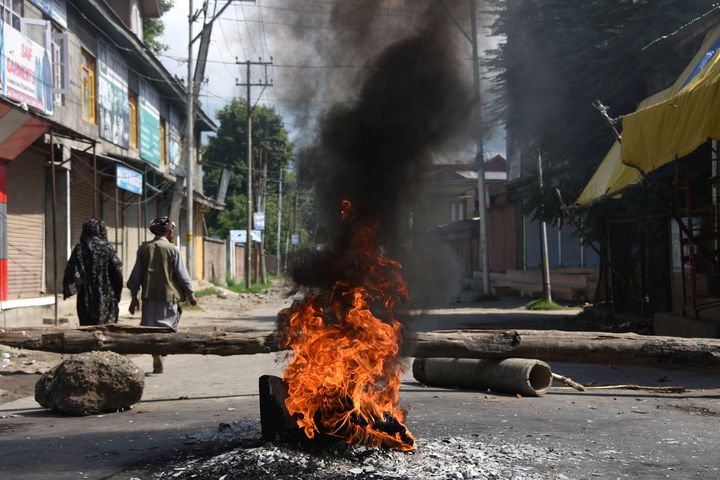 People walk past burning tires near a barricade during a protest against the abolishing of Article 370, on Aug. 20, 2019 in Srinagar, India. 