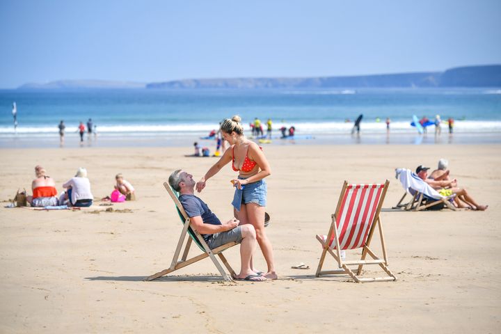 Sunbathers apply sunscreen during the hot sunshine on Towan beach in Newquay, Cornwall.