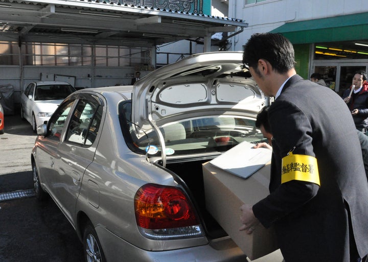 家宅捜索し、段ボール箱を車に積み込む労働基準監督署の職員ら