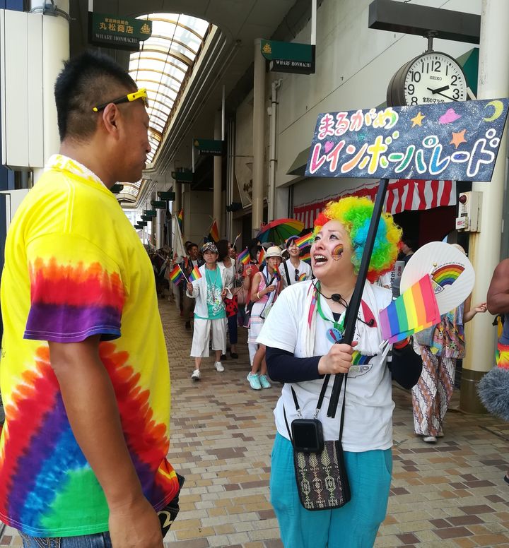 虹色のTシャツを着た矢野さん（左）に沿道で声を掛けられたパレード代表の藍川逸美さん＝香川県丸亀市、2019年8月25日