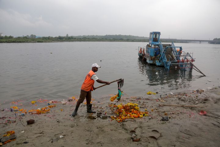 A worker removes worship materials that were thrown into the river Yamuna by devotees during the annual immersion ritual of Ganesh idols in an effort to minimize river pollution in New Delhi, India, Monday, Sept.24, 2018. Every year millions of devout Hindus immerse idols of god Ganesh into water bodies at the end of the Ganesh Chaturthi festival that celebrates the birth of the Hindu god.