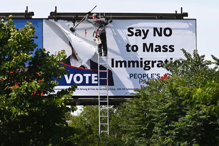 A worker removes a billboard featuring the portrait of People’s Party of Canada (PPC) leader Maxime Bernier and its message "Say NO to Mass Immigration" in Toronto, Ontario, Canada August 26, 2019. REUTERS/Moe Doiron