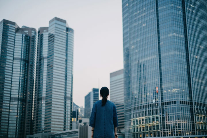 Rear view of woman looking towards city concrete jungle in downtown financial area