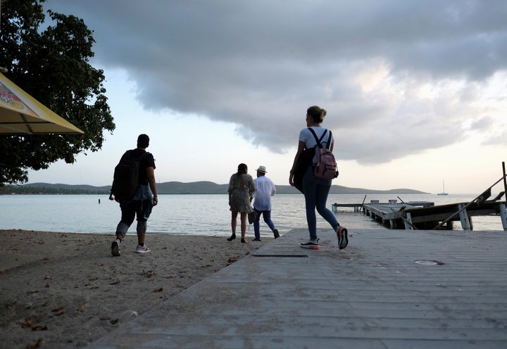 A group of people walk on the beach in the tourist zone of Boqueron as Tropical Storm Dorian approaches in Cabo Rojo, Puerto Rico August 26, 2019. REUTERS/Ricardo Arduengo