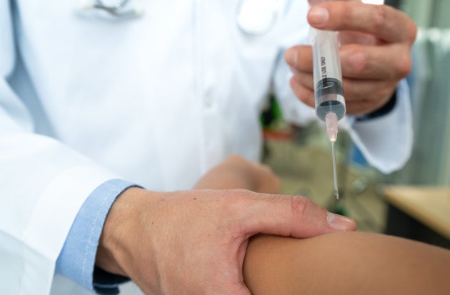Doctor using syringe to give in jection to patient in hospital