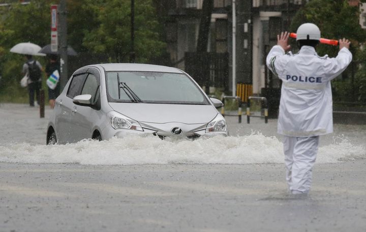 大雨で冠水した道路を進む車＝8月28日午前、佐賀市