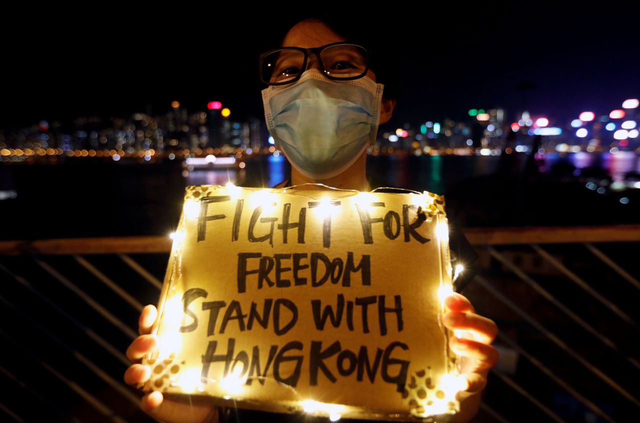 A woman holds a placard as protesters hold hands to form a human chain during a rally to call for political reforms along Tsim Sha Tsui and Hung Hom Promenade in Hong Kong, China, August 23, 2019. 