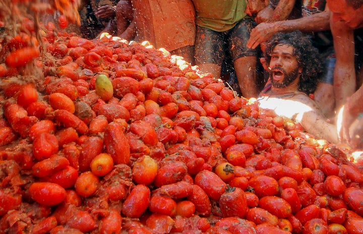 Revellers party during the annual "Tomatina" tomato fight fiesta, in the village of Bunol, near Valencia, Spain, Spain, Wednesday, Aug. 28, 2019. The party saw 145 tons of tomatoes offloaded from six trucks into crowds packing Bunol's streets for the midday hourlong battle Wednesday. (AP Photo/Alberto Saiz)