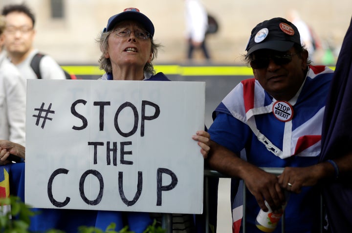 Anti-Brexit supporters wave flags and hold signs near the Houses of Parliament in central London, Wednesday, Aug. 28, 2019. British Prime Minister Boris Johnson asked Queen Elizabeth II on Wednesday to suspend Parliament, throwing down the gauntlet to his critics and causing outrage among opposition leaders who will have even less time to thwart a no-deal Brexit. (AP Photo/Matt Dunham)