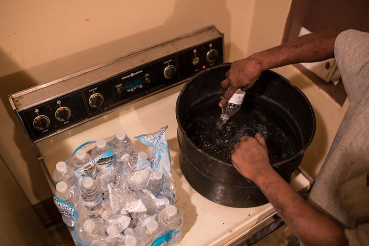 Flint resident Darryl Wilson, 46, empties a case of bottled water into a large pot to heat up for 45 minutes, allowing him to wash the dishes on Feb. 18, 2016. 