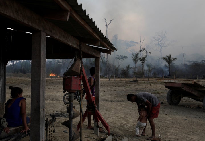 Residents are pictured while a fire burns a tract of Amazon jungle as it is cleared by loggers and farmers near Porto Velho, Brazil August 27, 2019. REUTERS/Ricardo Moraes