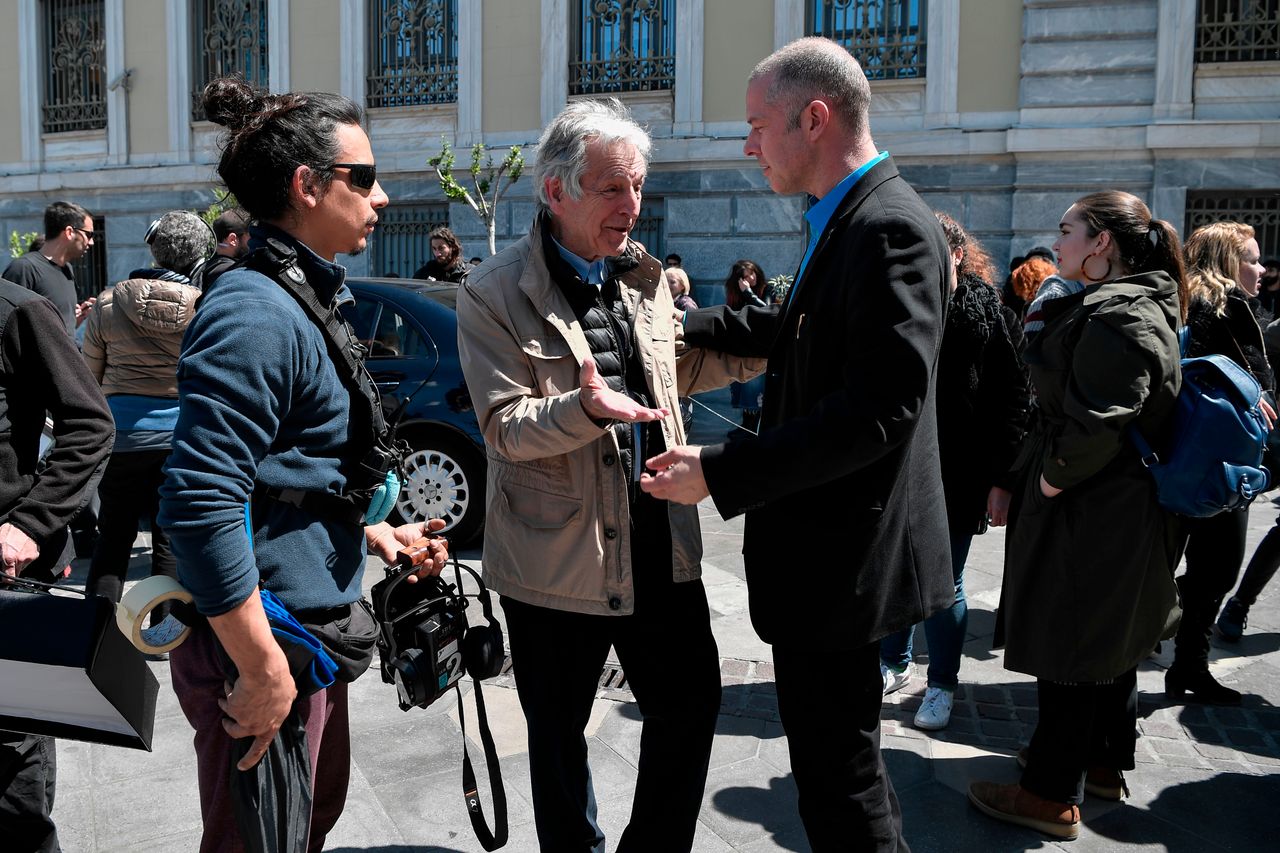 Greek-French film director Costas-Gavras (C) talks with Greek actor Christos Loulis playing the role of the former Greek Finance minister Yanis Varoufakis during the shooting of the film 'Adults in the room' in central Athens on April 11, 2019. - The political film is based on Varoufakis' book. (Photo by Louisa GOULIAMAKI / AFP) (Photo credit should read LOUISA GOULIAMAKI/AFP/Getty Images)