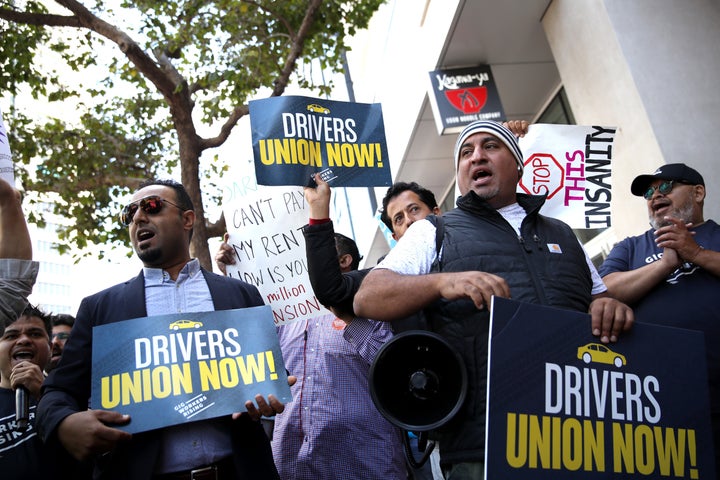 Rideshare drivers hold signs during a protest outside Uber headquarters in San Francisco in support of California labor legis