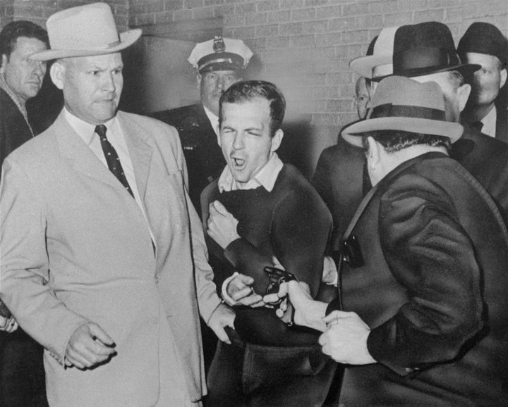 Lee Harvey Oswald, the assassin of President John F. Kennedy, reacts as Dallas night club owner Jack Ruby, foreground, shoots at him at point-blank range in a corridor of Dallas police headquarters, Nov. 24, 1963. At left is Detective Jim Leavelle. 