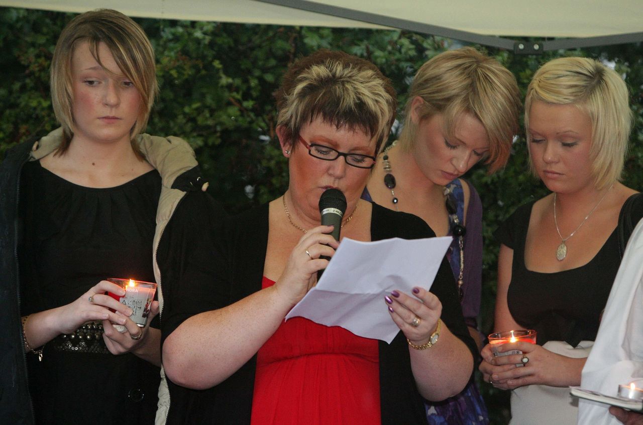 Helen Newlove reads a tribute to her husband Garry Newlove with her three daughters by her side at the end of a candle lit walk to the point where he fell on the one year anniversary of his death.