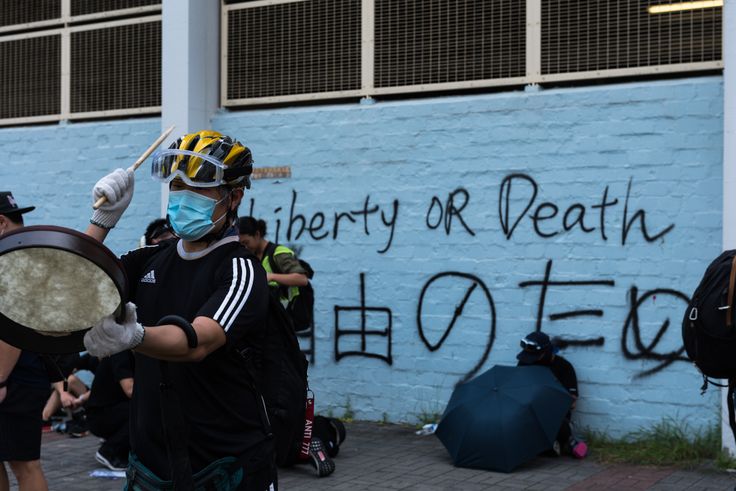 HONG KONG, CHINA - 2019/08/24: A protester drums in front of a wall with graffiti during the demonstration.Thousands of anti-government protesters marched in opposition to the extradition bill. Protesters eventually clashed with police, leading to widespread of police dispersal operations and multiple arrests. (Photo by Aidan Marzo/SOPA Images/LightRocket via Getty Images)