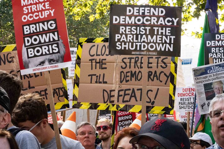 Various people are seen holding banners as part of the Stop the Coup protests on Downing Street in London.