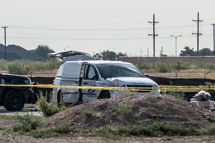 A damaged police vehicle and U.S. Postal Service van are seen blocked off with tape near where a gunman was shot and killed following a deadly shooting on Saturday.