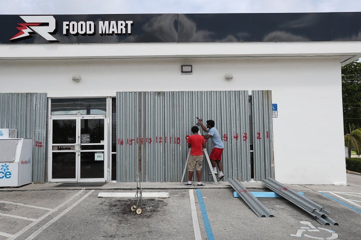 Workers place shutters over the windows of a Food Mart store in Riviera Beach, Florida.